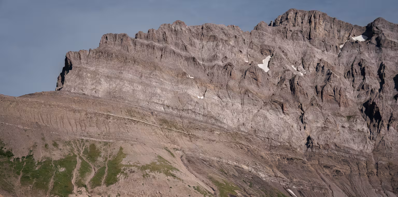 Hiker with backpack looking up at a large mountain.