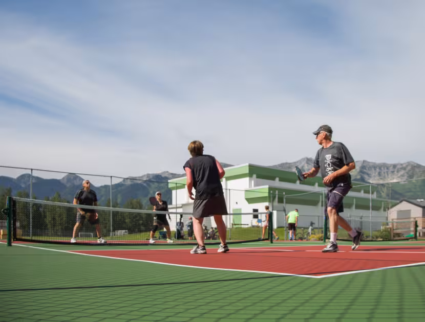 Two men playing pickleball on a court with mountains in the background.