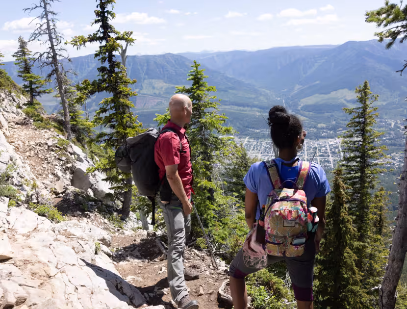 Two hikers on a mountain trail overlooking a valley.