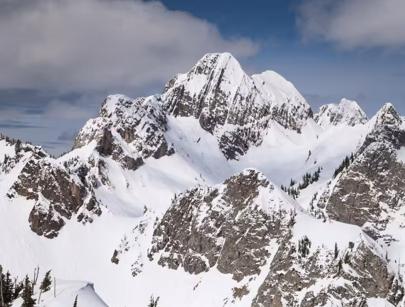 Snow-capped mountains under a blue sky with white clouds.