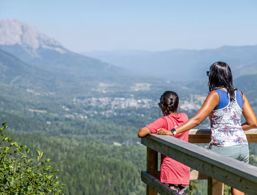 Woman and child looking out at a mountain view from a deck.