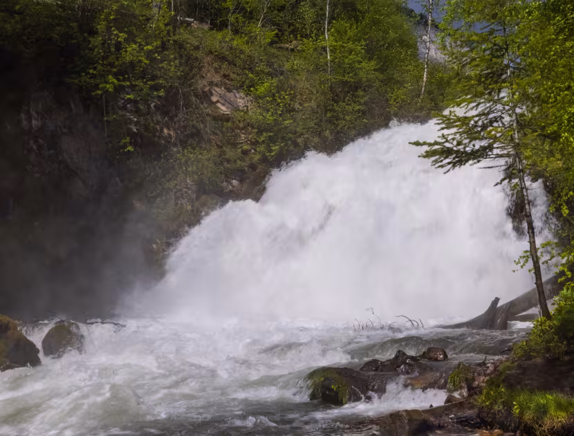 Waterfall cascading down rocky slope surrounded by trees.