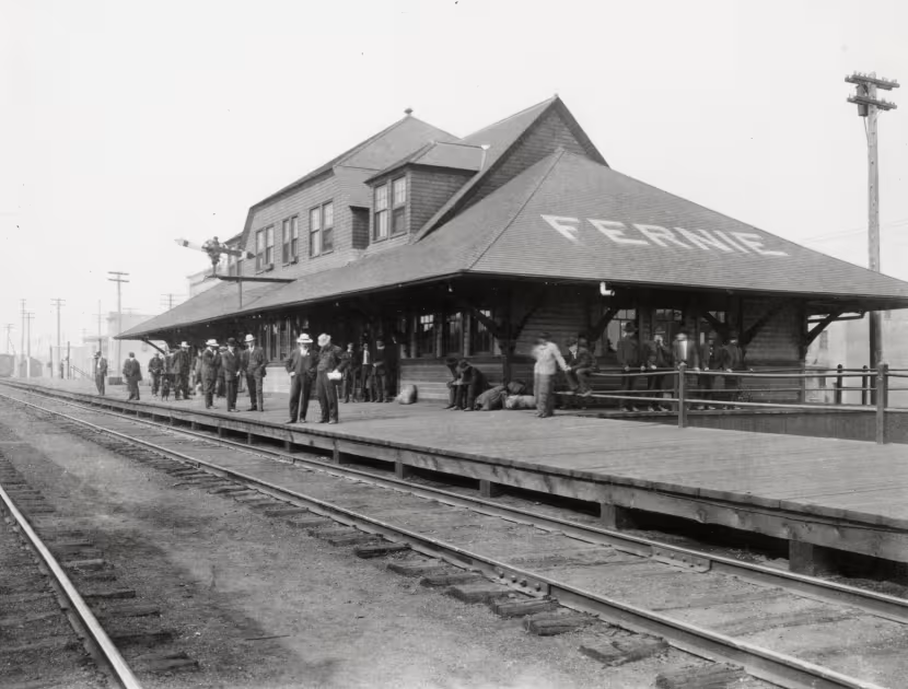 Black and white photograph of the Fernie train station with people on platform.