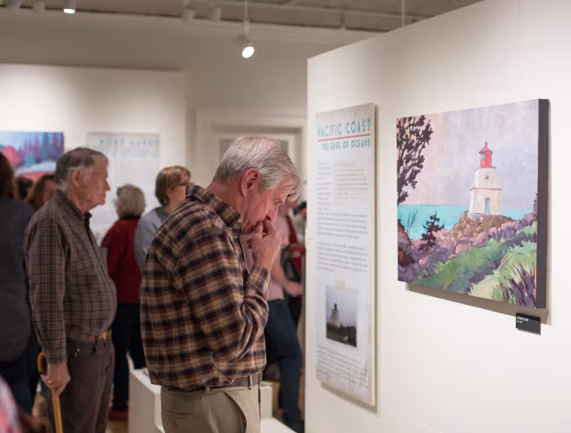 People looking at colourful artwork in a gallery.