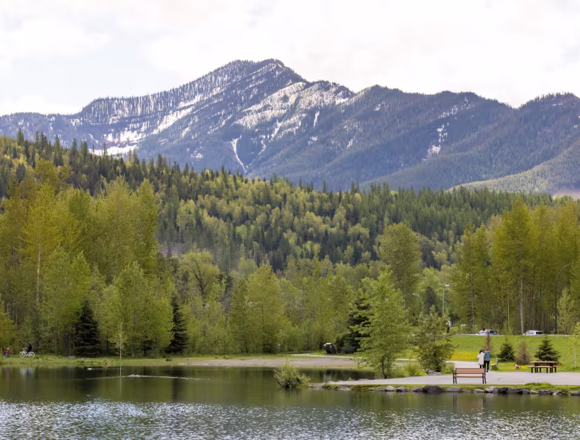 Serene Maiden lake in Fernie with trees and mountain range in background.