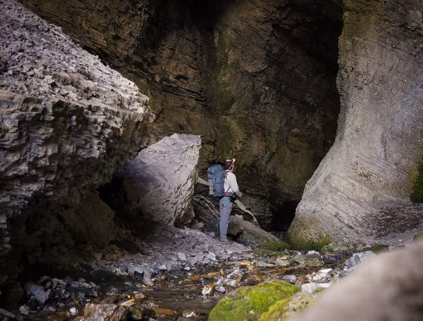Person in white shirt and blue jeans standing in the Bisaro cave entrance.