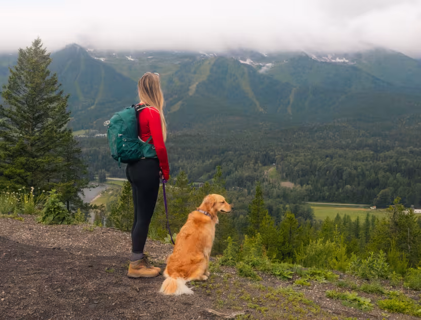 Woman and dog on mountain trail, overlooking the Elk Valley and Lizard Range mountains.
