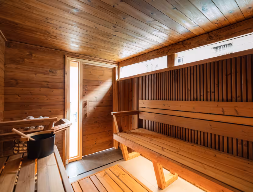 Cozy wooden Finnish sauna interior with bench and open door.