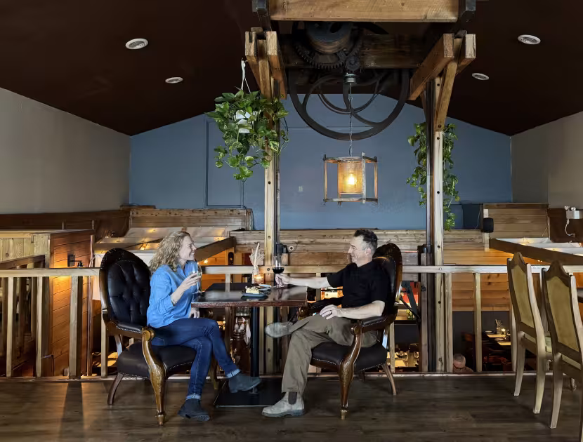Two people seated at a table in a warmly lit rustic loft.