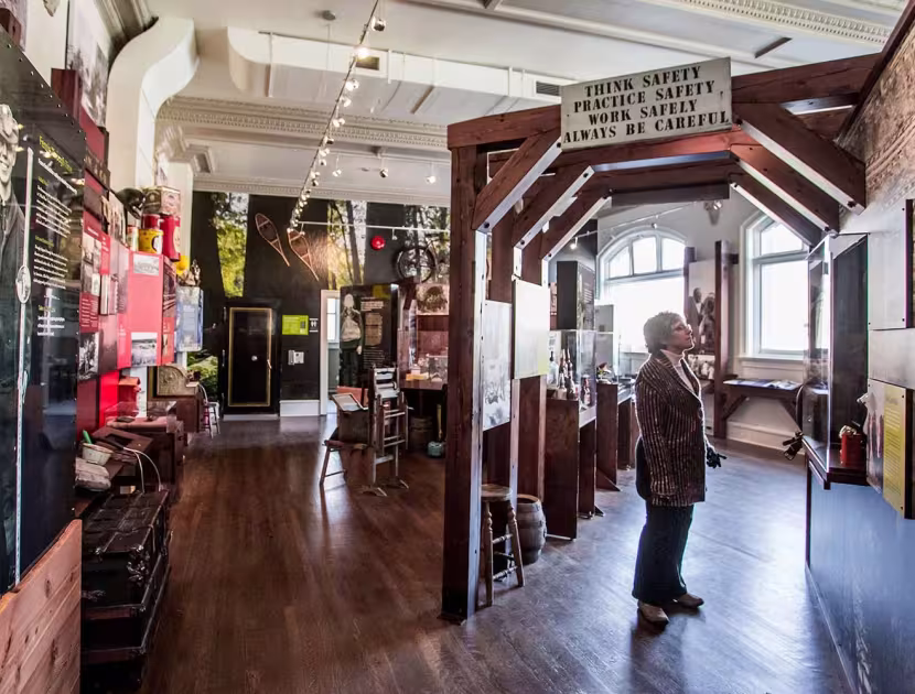 Interior the Fernie Museum, with a person standing; dark wood floors and decor; natural light.