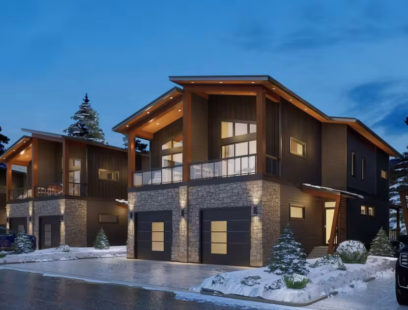 Snowy suburban duplex with brown exterior, lit windows, and balcony; evening sky.