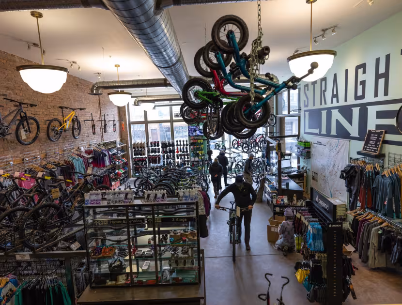 Bicycle shop interior with bikes on racks and hanging from ceiling.