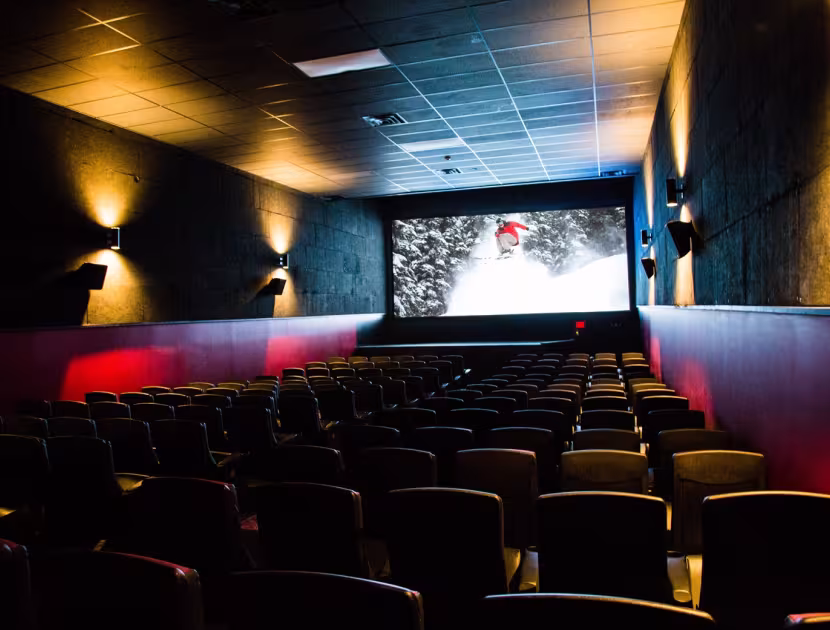Empty movie theater with red and yellow lighting, screen at the front.