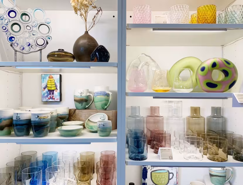 A white shelving unit with various decorative glassware, including vases, bowls, and cups, on display.